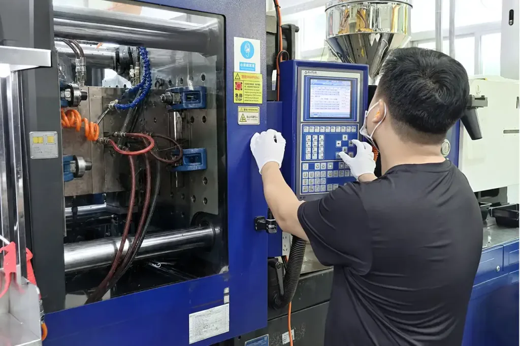 Plastic Injection molding technician operating a control panel to monitor plastic injection molding process to meet quality standards.