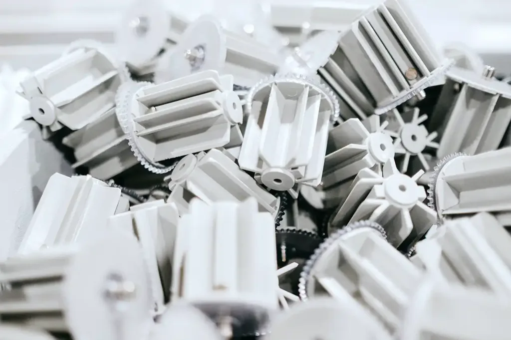 Batch of precision-engineered white plastic gears and ribbed components manufactured via plastic injection molding.