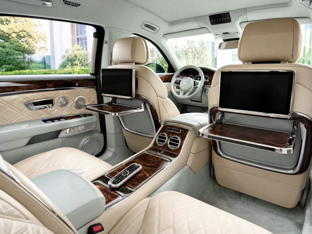 Luxury rear passenger compartment with fine details, chrome trim, cream leather, and executive picnic tables.